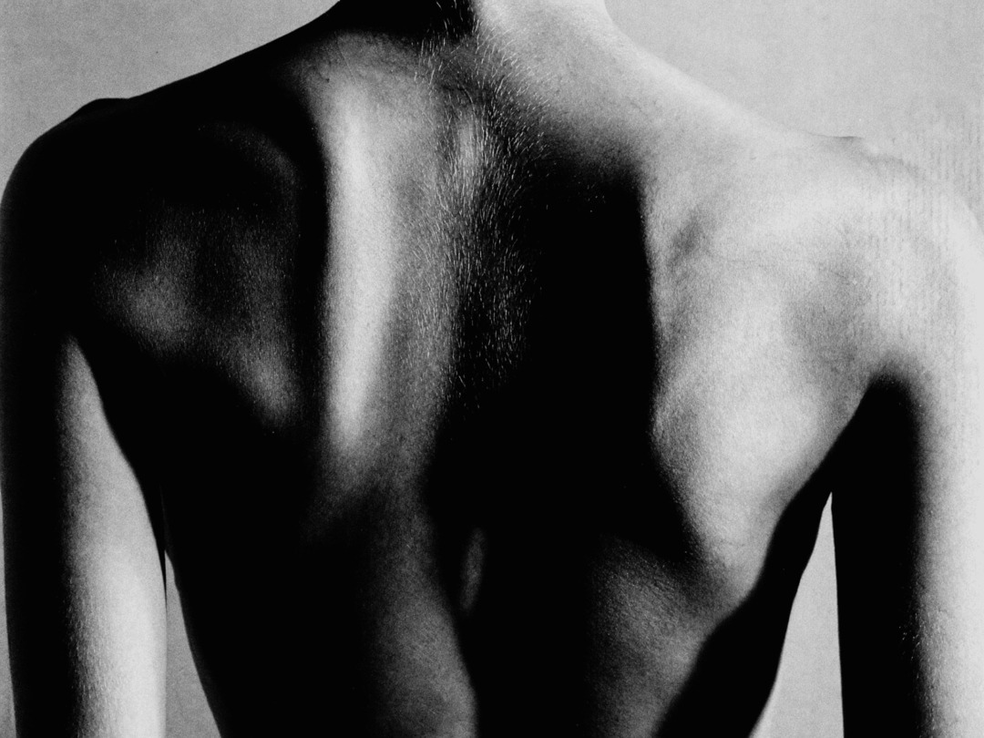 Black-and-white close-up of a person's torso and shoulder