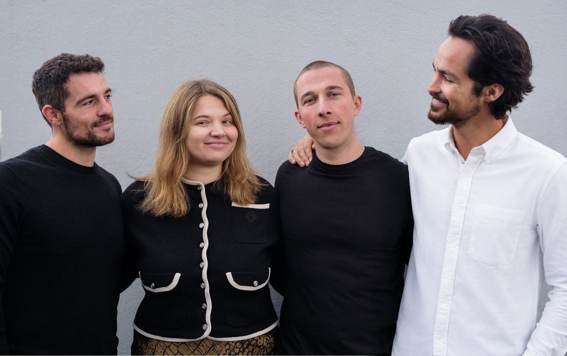Four members of the Peers Capital team standing together against a light wall